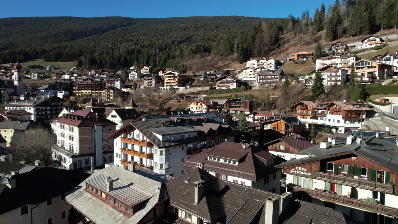 Veduta aerea della Val Gardena, Italia, con condomini e case in una soleggiata giornata di primavera, ripresa con drone