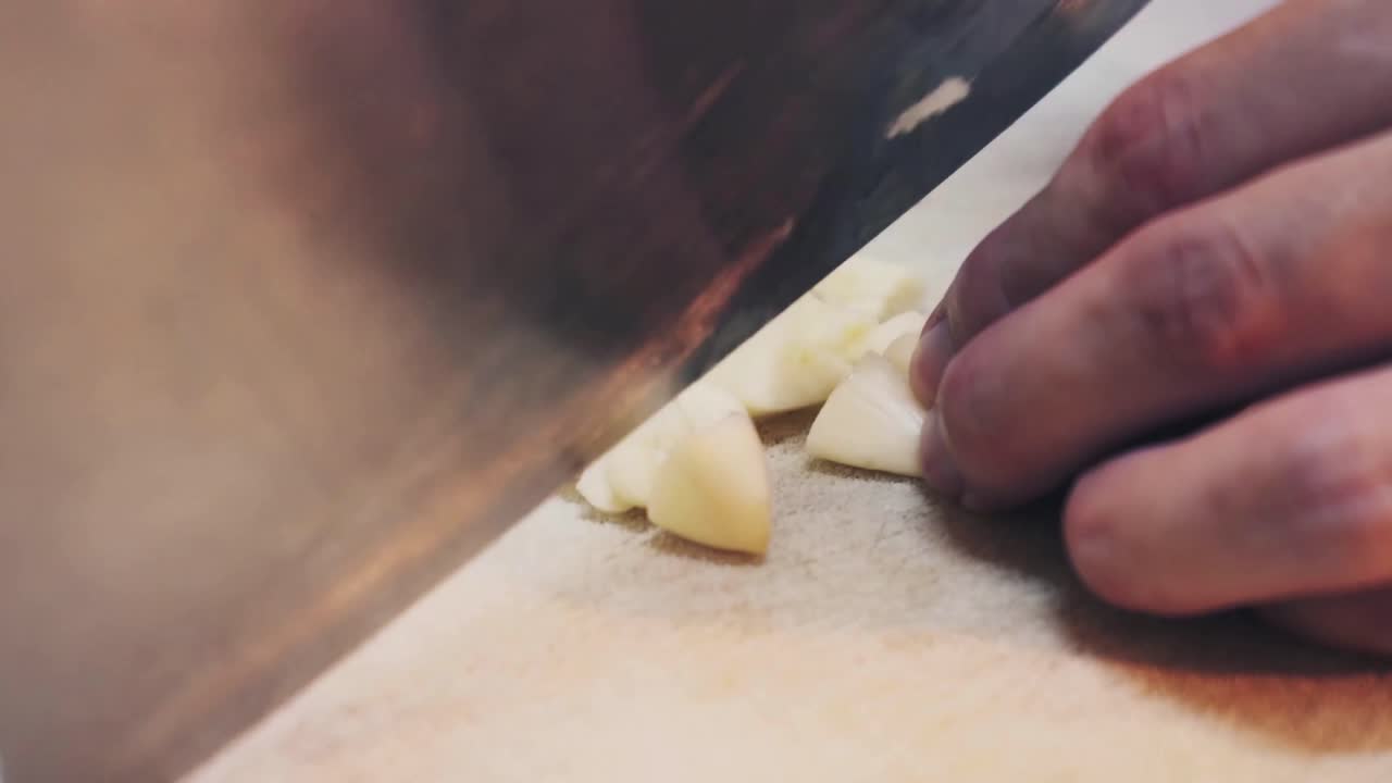 A chef slices garlic on chopping board close up
