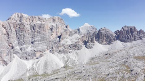 aerial panoramic shot of fanes nature park with gigantic mountains against blue sky and sun - dolomites,italy