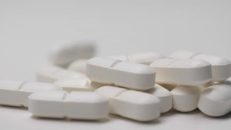 White-pills-sliding-on-white-background-in-slow-motion