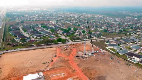 una toma de un dron de 4k de un sitio de construcción con una grúa en él trabajando en una torre celular y en el fondo un montón de casas residenciales en florida