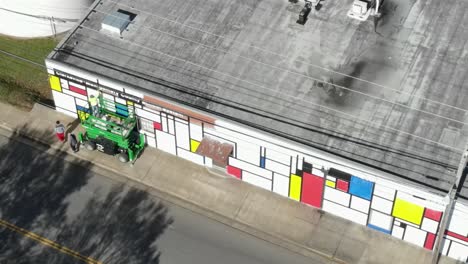 toma de un artista local pintando un mural en un elevador de tijera