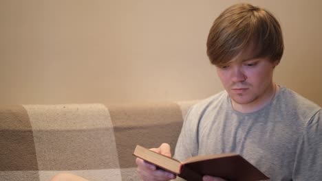 hombre leyendo un libro en un sofá