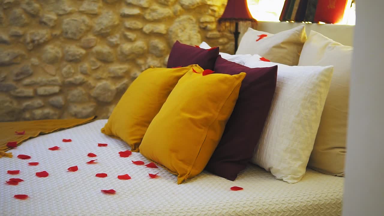 configuración de cama romántica con pétalos de rosa y almohadas