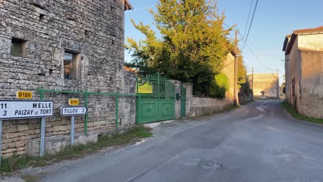 Road-junction-in-French-village-showing-old-building-and-green-gates