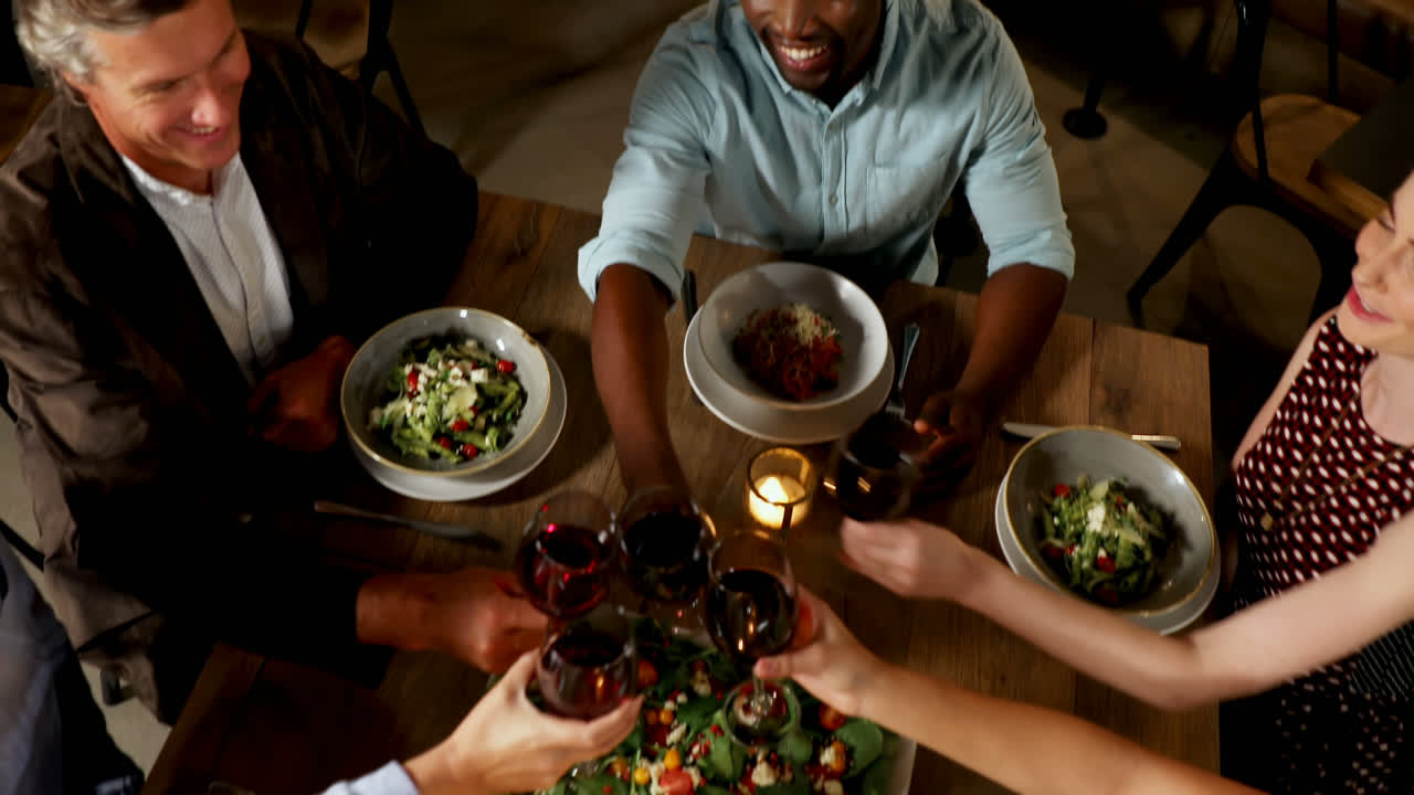 Group of friends toasting glasses while having dinner 4K 4k