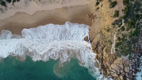 Top-down-Shot-Of-White-Foamy-Waves-Splashing-In-Slow-Motion-On-The-Shore-In-Knight-Beach,-Port-Elliot,-Australia---aerial-drone