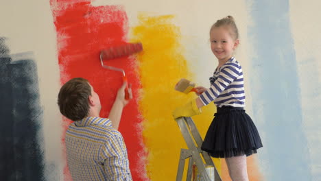 father and daughter painting walls in bright colors