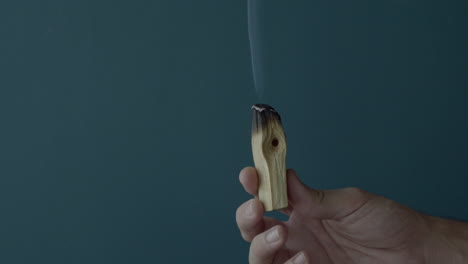 Hand-holding-a-burning-Palo-Santo-incense-and-takes-it-off-the-scene