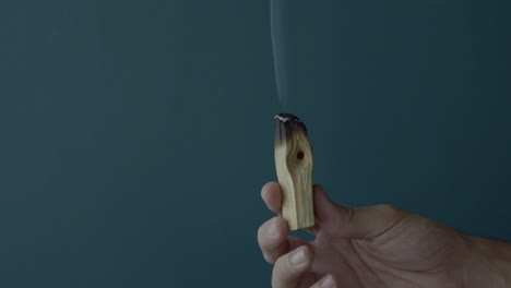 mano sosteniendo un incienso de palo santo ardiendo y lo saca de la escena