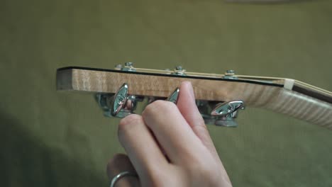 guitarrista afinando la guitarra acústica girando los cabezales de la máquina o clavijas de afinación en el clavijero