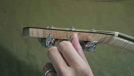 guitarist tuning the acoustic guitar by turning the machine heads or tuning pegs on the headstock