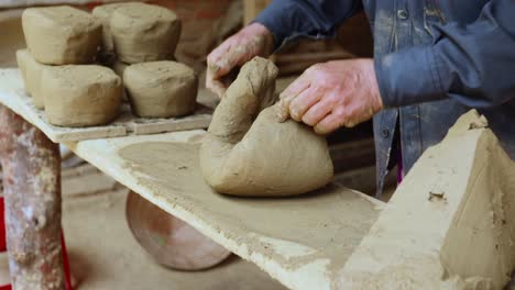 hand pressing potters clay on grungy messy bench