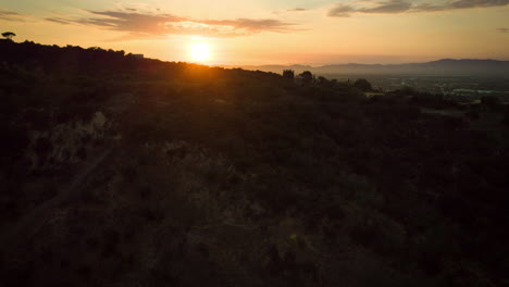 Sobrevuelo-De-Colinas-Silueteadas-Revisando-Una-Hermosa-Puesta-De-Sol-Sobre-Una-Ciudad-De-Valle-Brumoso