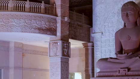 isolated-red-stone-jain-god-holy-statue-in-meditation-from-different-angle-video-is-taken-at-Shri-Digamber-Jain-Gyanoday-Tirth-Kshetra,-Nareli-Jain-Mandir,-Ajmer,-Rajasthan,-India