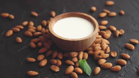 amond seeds with bowl of fresh natural milk placed on black stone background