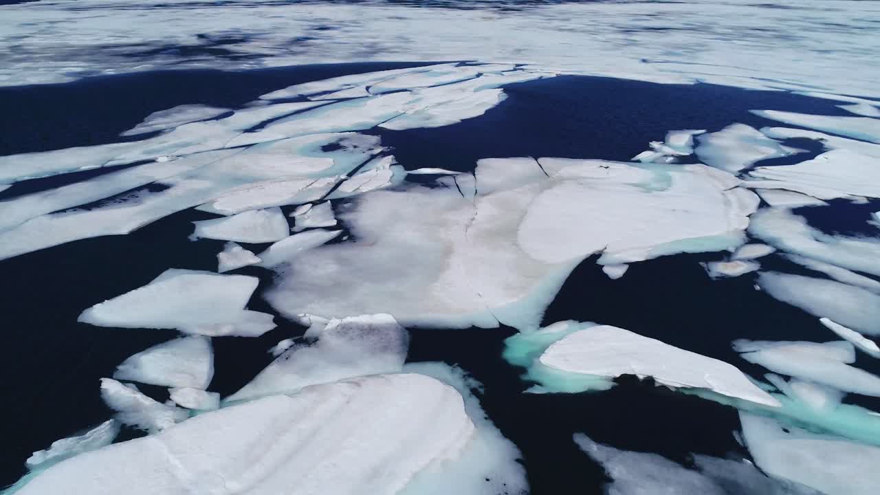 Aerial over a high mountain lake with large melting ice sheets and icebergs in Iceland 1