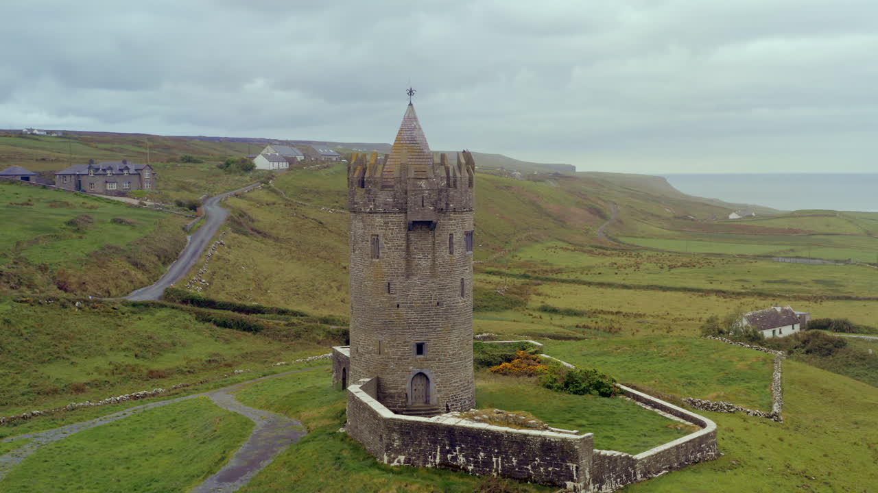 Slow aerial orbit of Doonagore Castle, with the cliffs of moher on Background
