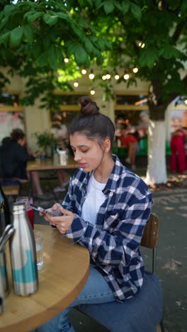 young woman using phone in outdoor cafe