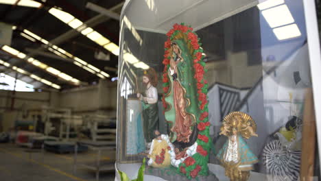 a slow dolly in of a virgin mary and catholic saints in a mexican warehouse - industrial plant