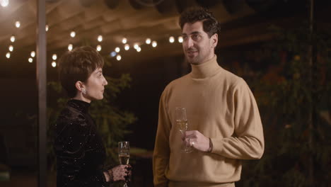 elegant woman and handsome man talking and laughing together at new year's eve party