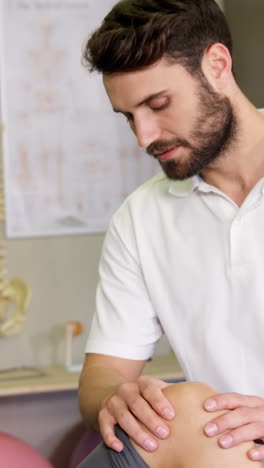 fisioterapeuta masculino dando masaje de rodilla a una paciente femenina