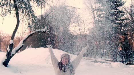 smiling girl throwing snow to air in slow motion in snow winter season outside