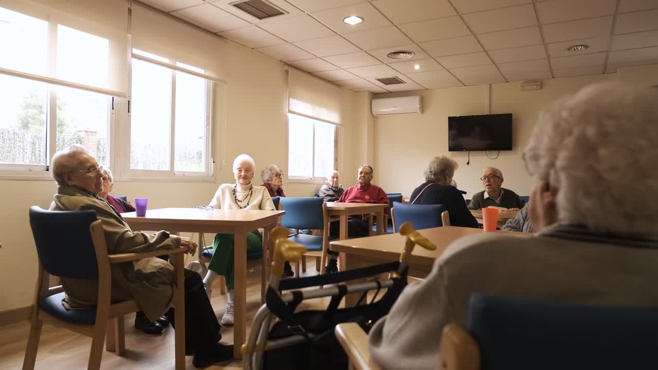Elderly men and women sitting in nursing home canteen