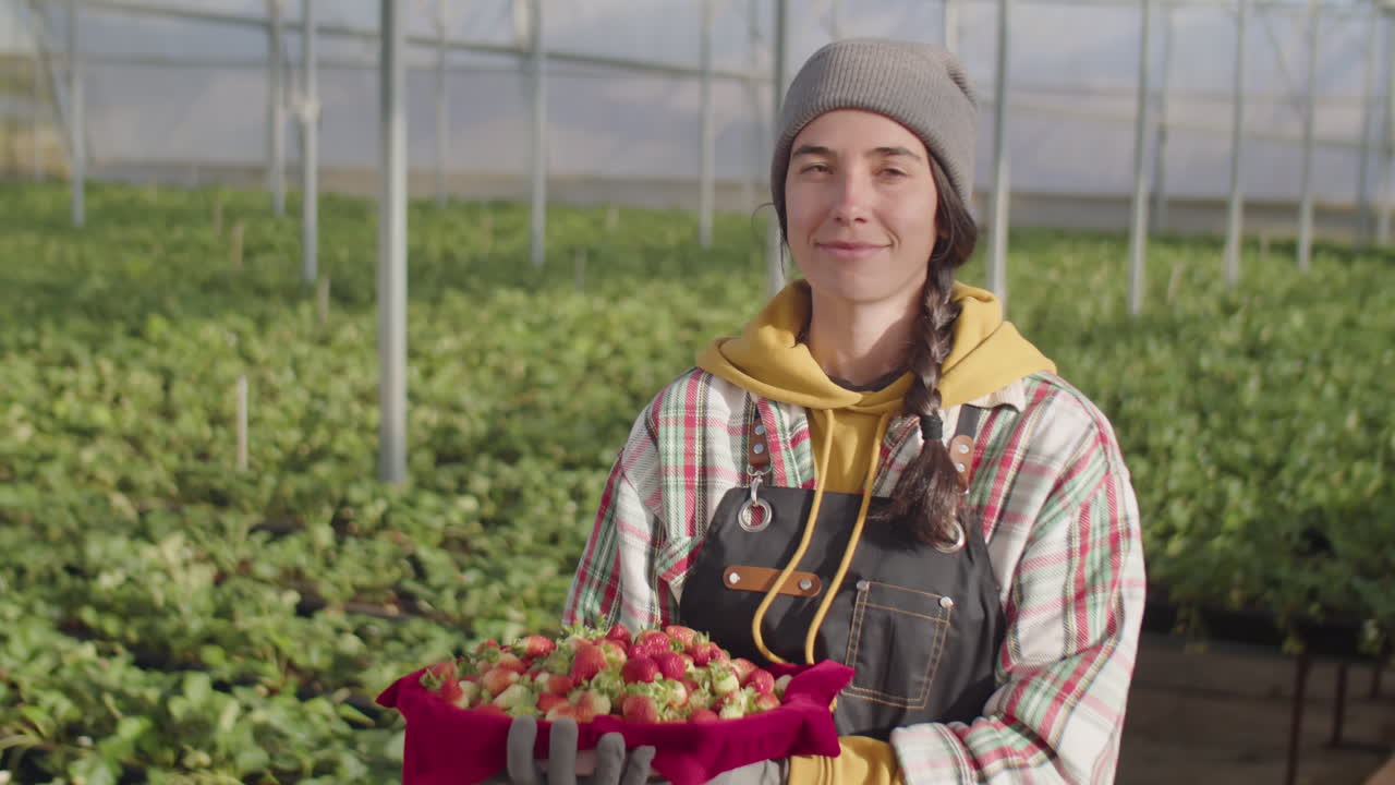 Portrait of Happy Female Farm Worker with Ripe Strawberry