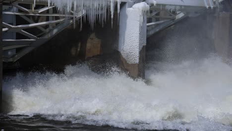river flowing through dam with some ice on dam close up in slow motion.