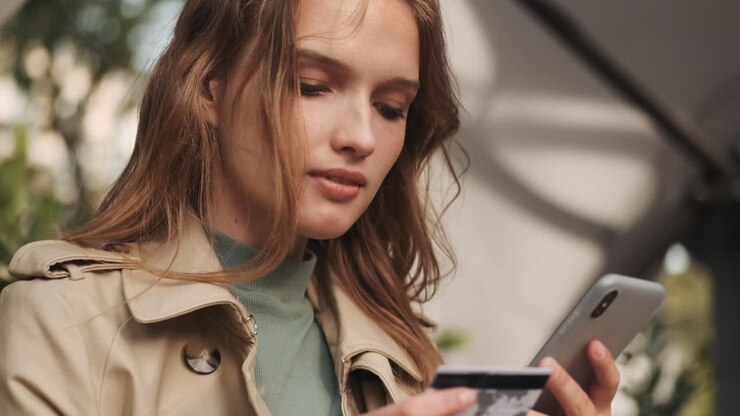 Étudiante caucasienne faisant du shopping en ligne sur son smartphone en extérieur