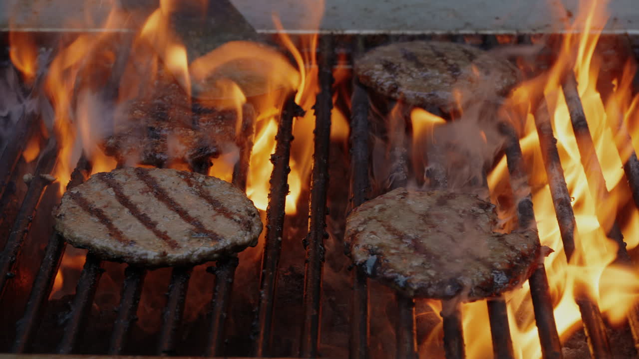 Hamburger su barbecue a carbone untuoso e fumoso in un pomeriggio estivo su griglia commerciale al rallentatore