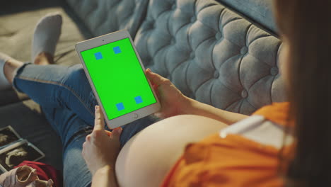 pregnant woman holding a tablet with green screen