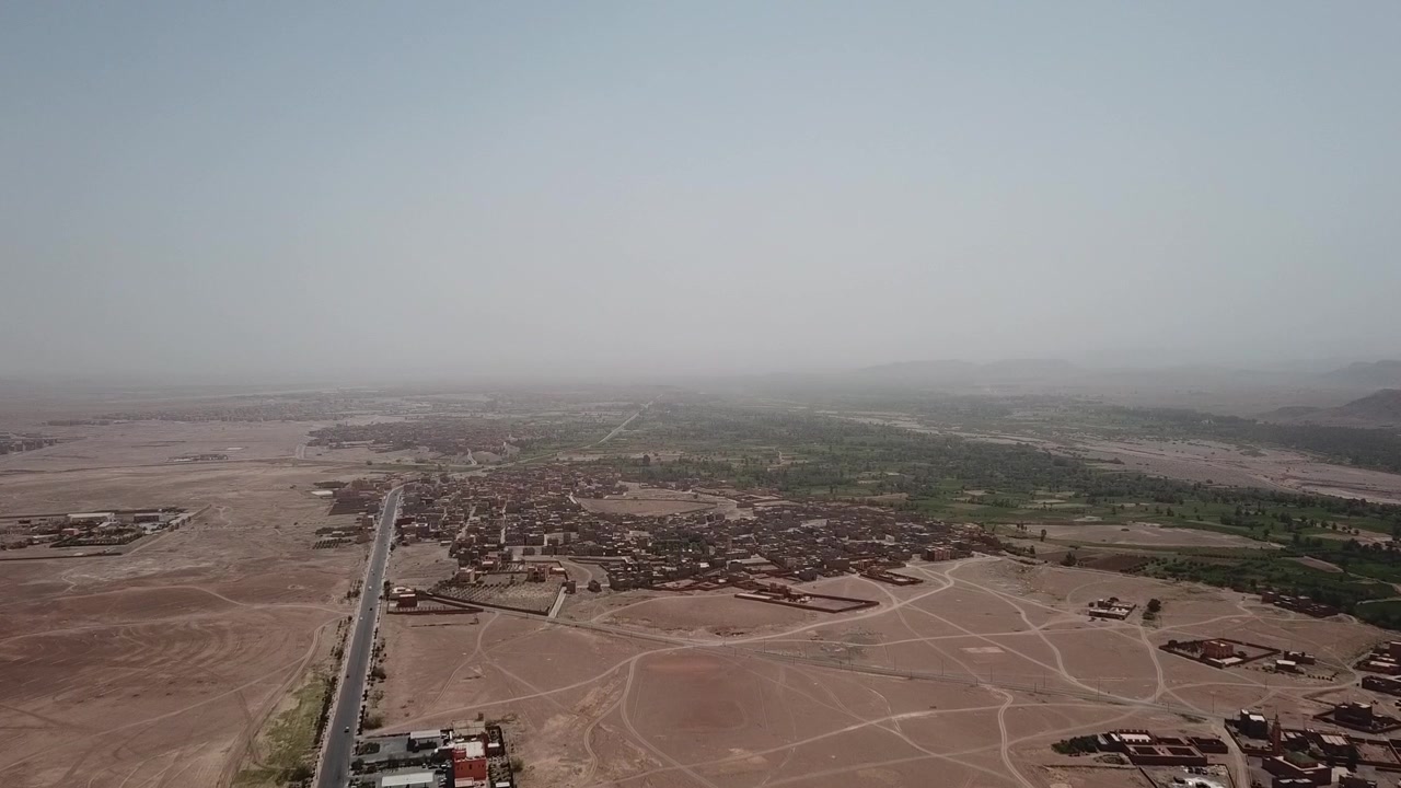 Vista aerea con drone di Ouarzazate, che mostra i suoi paesaggi di oasi, i dintorni desertici e il ruolo strategico come porta del Marocco verso il Sahara.
