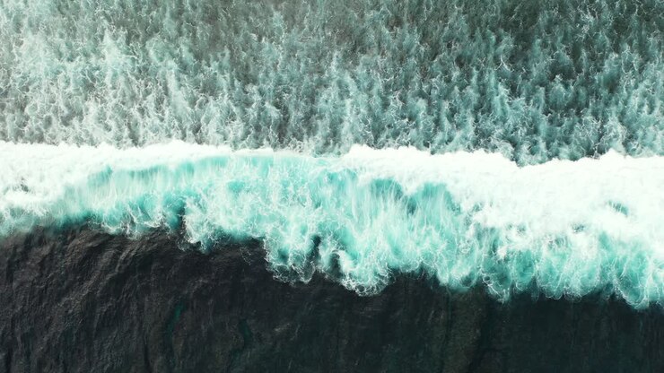 Big ocean waves splashing and foaming on seashore, creating abstract beautiful texture of dramatic motion, copy space, top down view