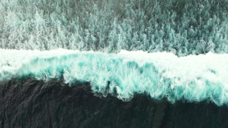 big ocean waves splashing and foaming on seashore, creating abstract beautiful texture of dramatic motion, copy space, top down view