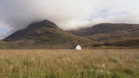 an isolated house on a grassy field in the mountains of scotland on the isle of skye