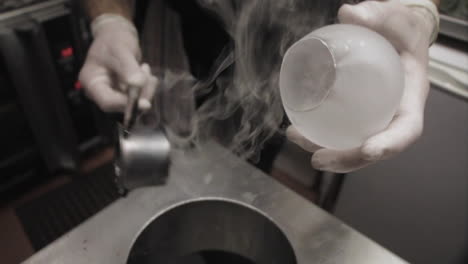 a chef cutting a hole in an isomalt sugar sphere for dessert