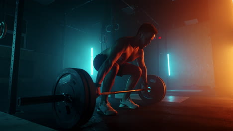 muscular fitness man doing push a barbell over his head in modern fitness center. functional training. snatch exercise. slow motion color led light saturated bright colors