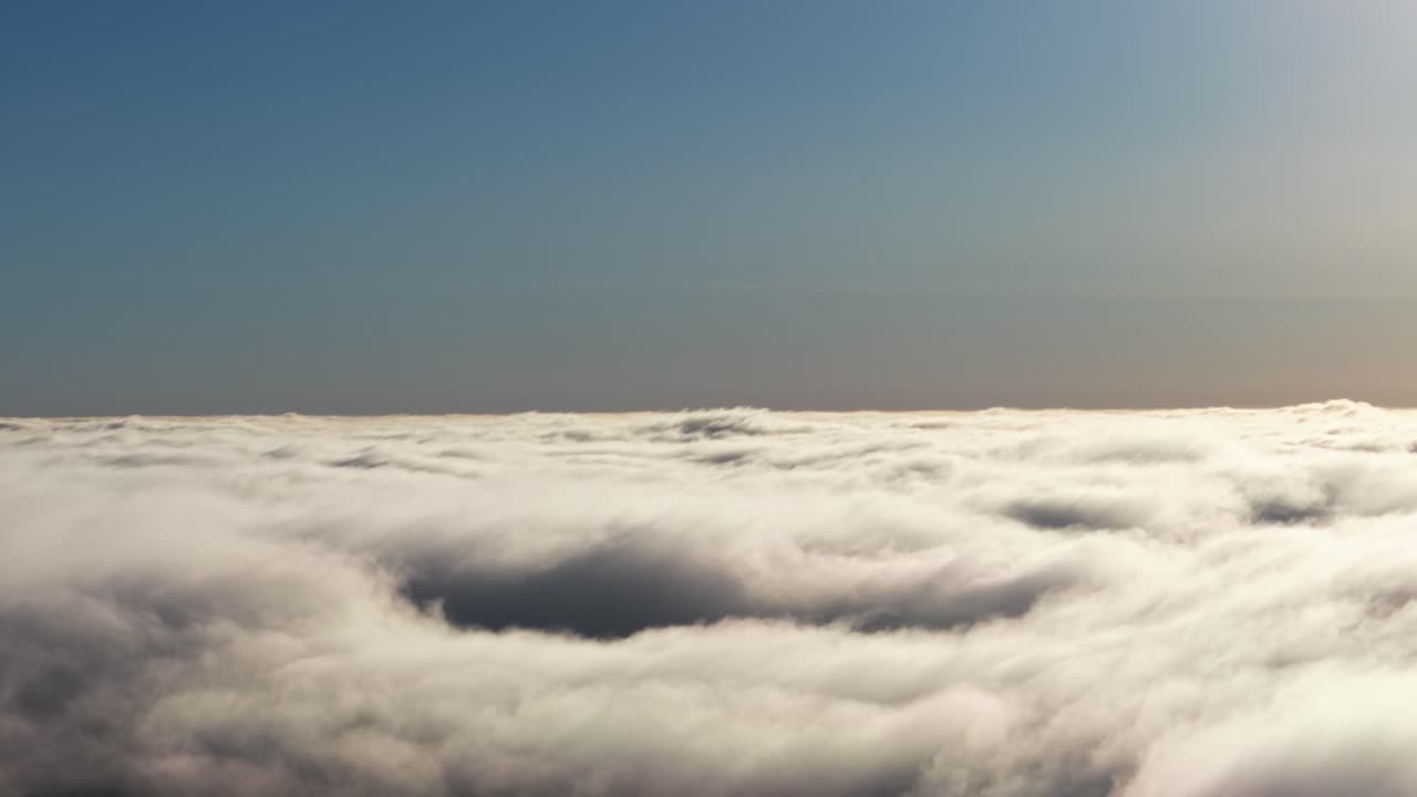 Rullende skylag, der danner et tekstureret tæppe under en klar himmel med farveovergang.