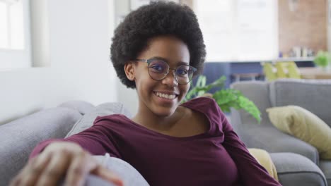 Portrait-of-smiling-african-american-teenage-girl-sitting-on-sofa-in-living-room