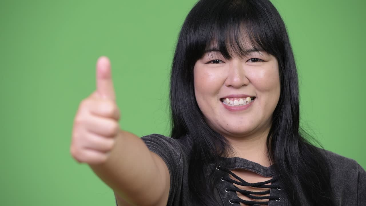 Happy overweight Asian woman giving thumbs up