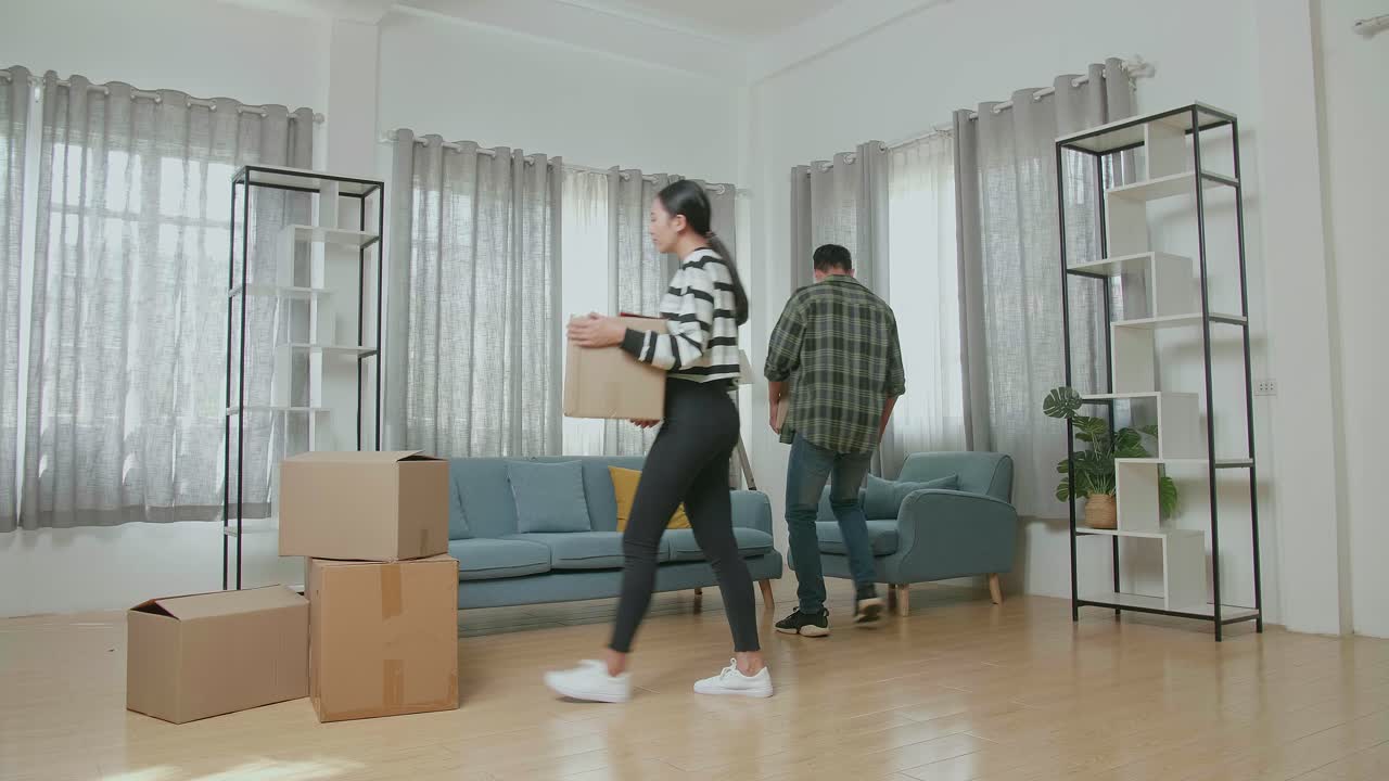 una joven pareja asiática feliz celebrando el final de llevar cajas de cartón con cosas a una nueva casa. se mudan a una nueva casa juntos