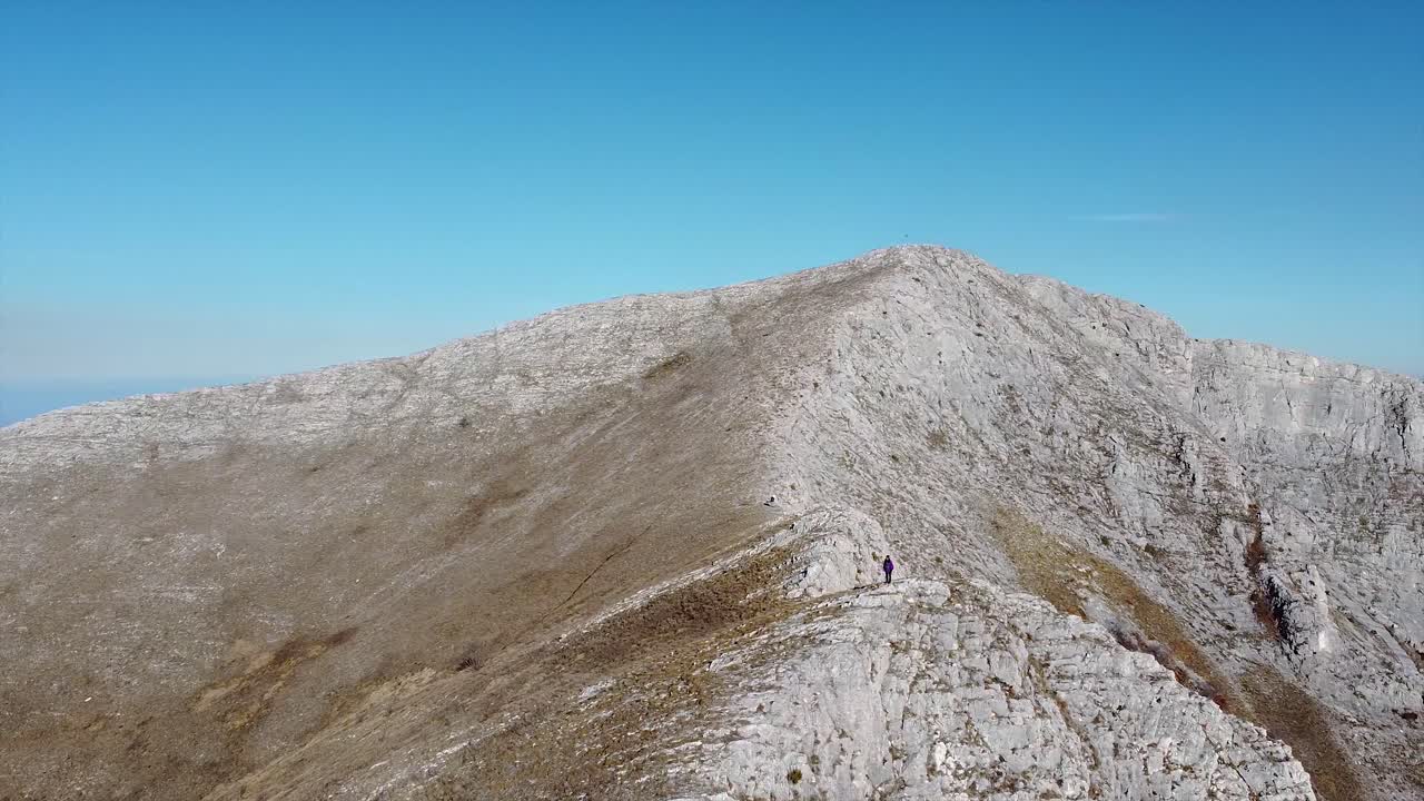 excursionista de pie en la cima de la montaña drone shot