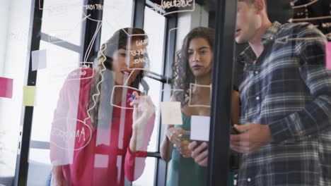 Diverse-creative-colleagues-in-discussion-making-notes-on-glass-wall-in-office,-slow-motion