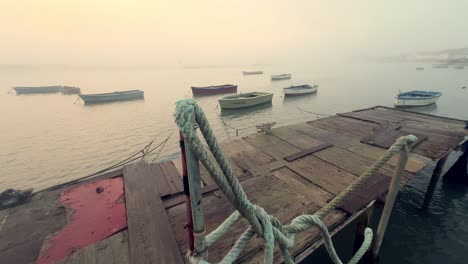 strolling along an aged and weathered wooden boardwalk, with small fishing boats peacefully afloat in the water