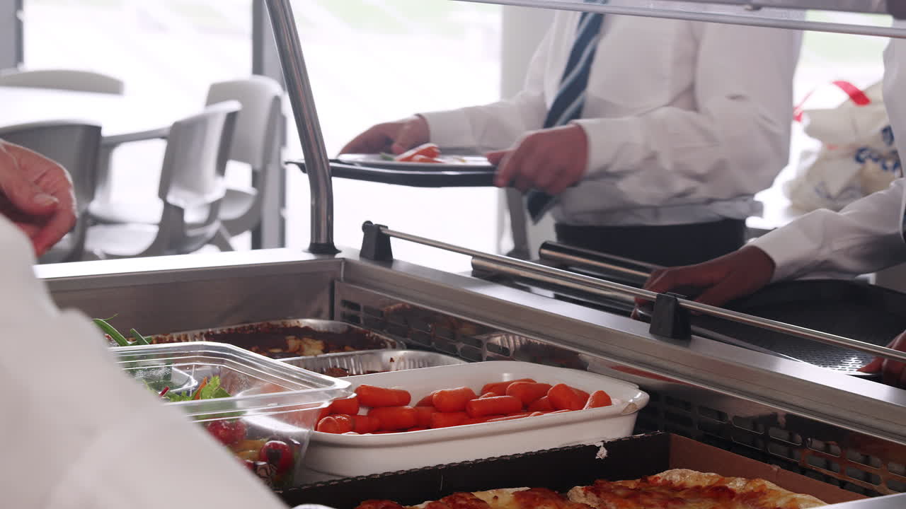 primer plano de estudiantes de secundaria vestidos con uniforme siendo servida comida en la cantina
