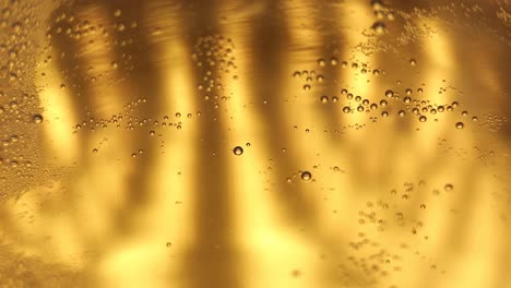 Macro-close-up-of-a-glass-of-beer---ale-beverage-with-active-fizzy-bubbles-of-gas,-predominantly-carbon-dioxide-inside-clear-glass