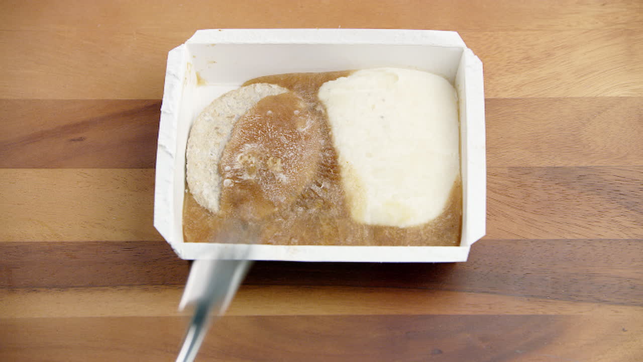 comida empacada en hielo congelado duro como una roca con una persona tratando de romperla con un tenedor