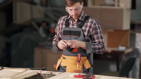 Handsome-young-man-in-carpenter's-work-uniform-puts-on-portable-headphones